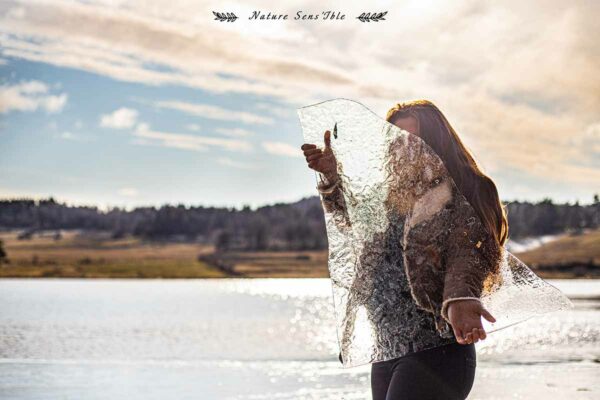 Portrait femme avec morceau de glace au lac du moulinetPortrait d’une femme enceinte avec un paysage enneigé sur l’Aubrac – Photo shooting extérieur